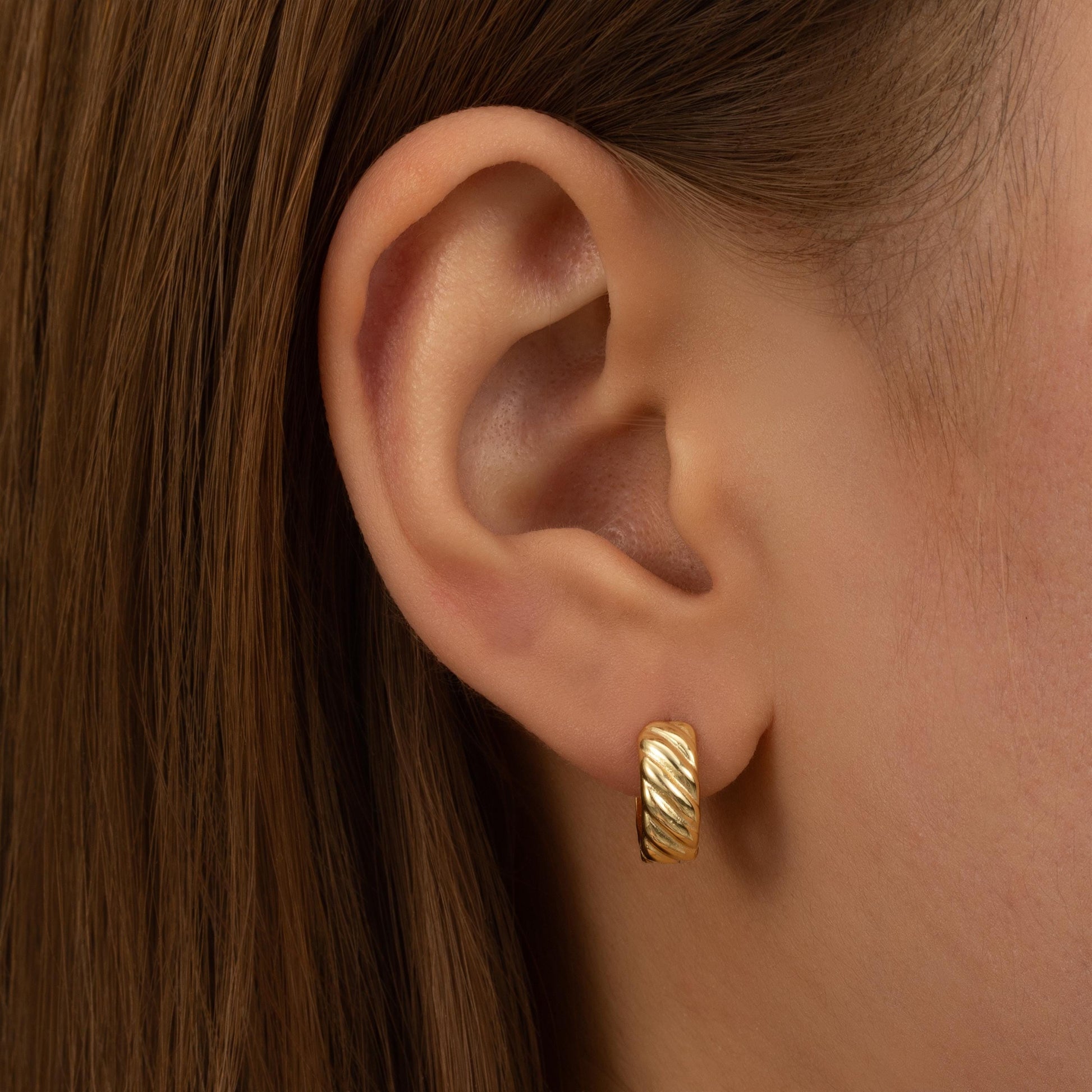 a close up of a person wearing a pair of earrings