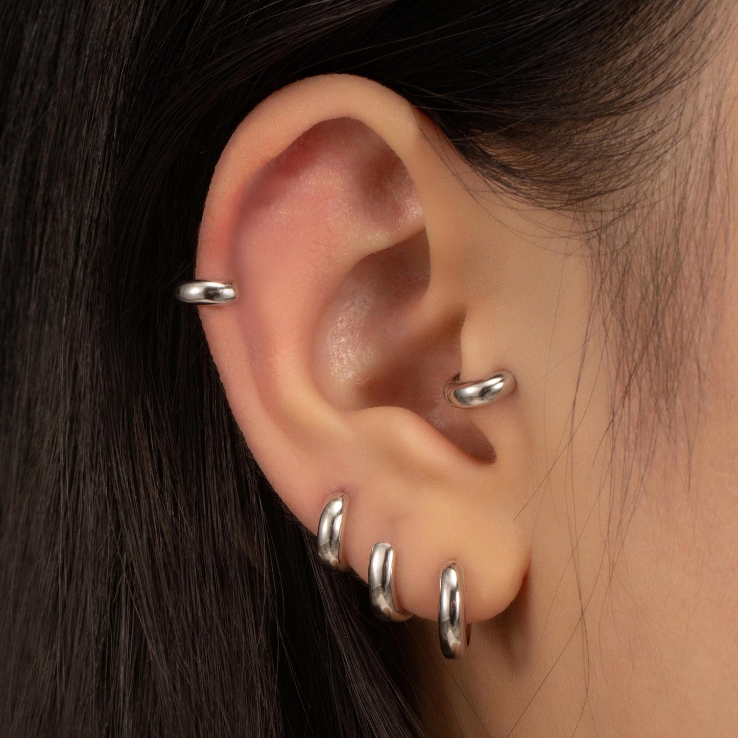 a close up of a person&#39;s ear with three piercings