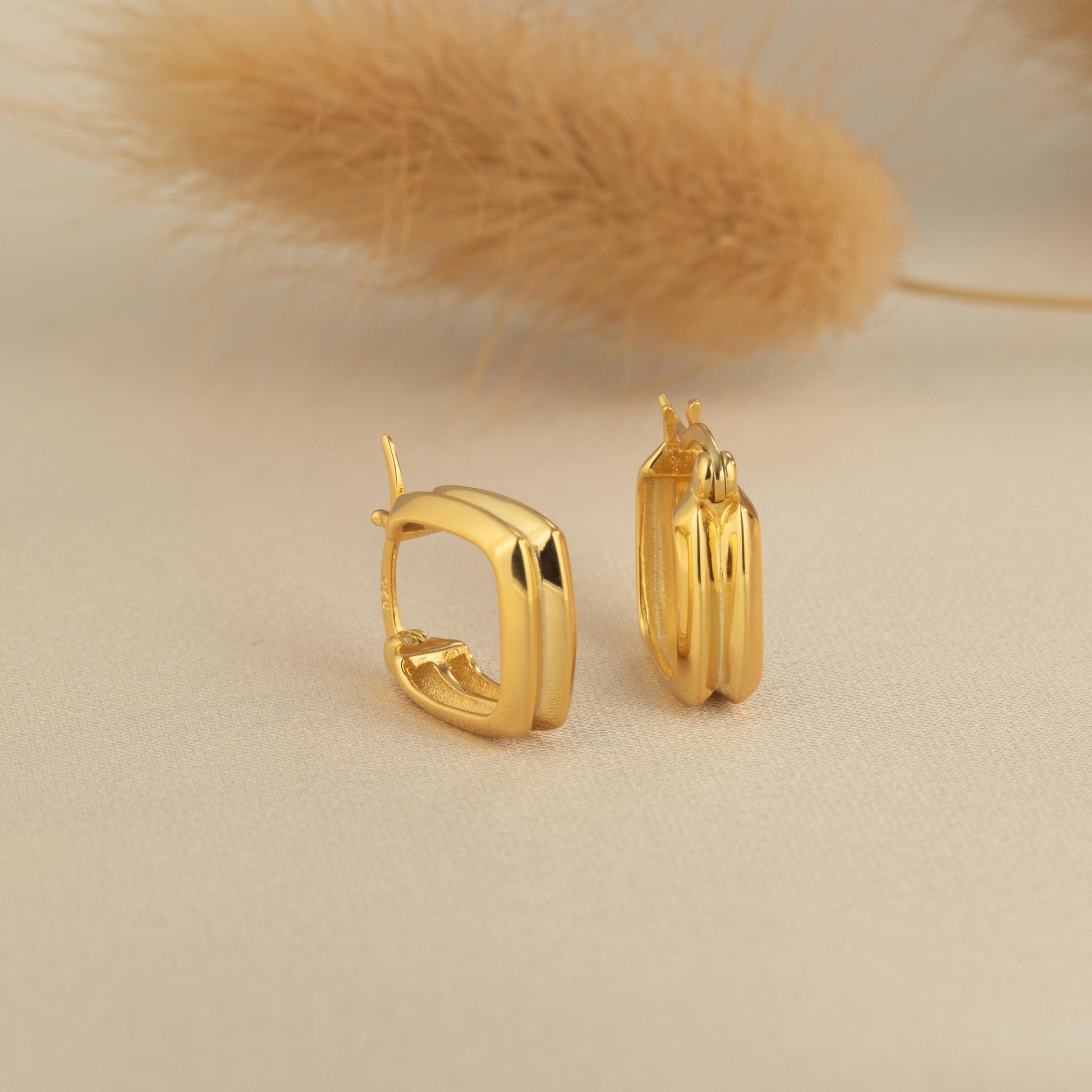 a pair of gold earrings sitting on top of a table