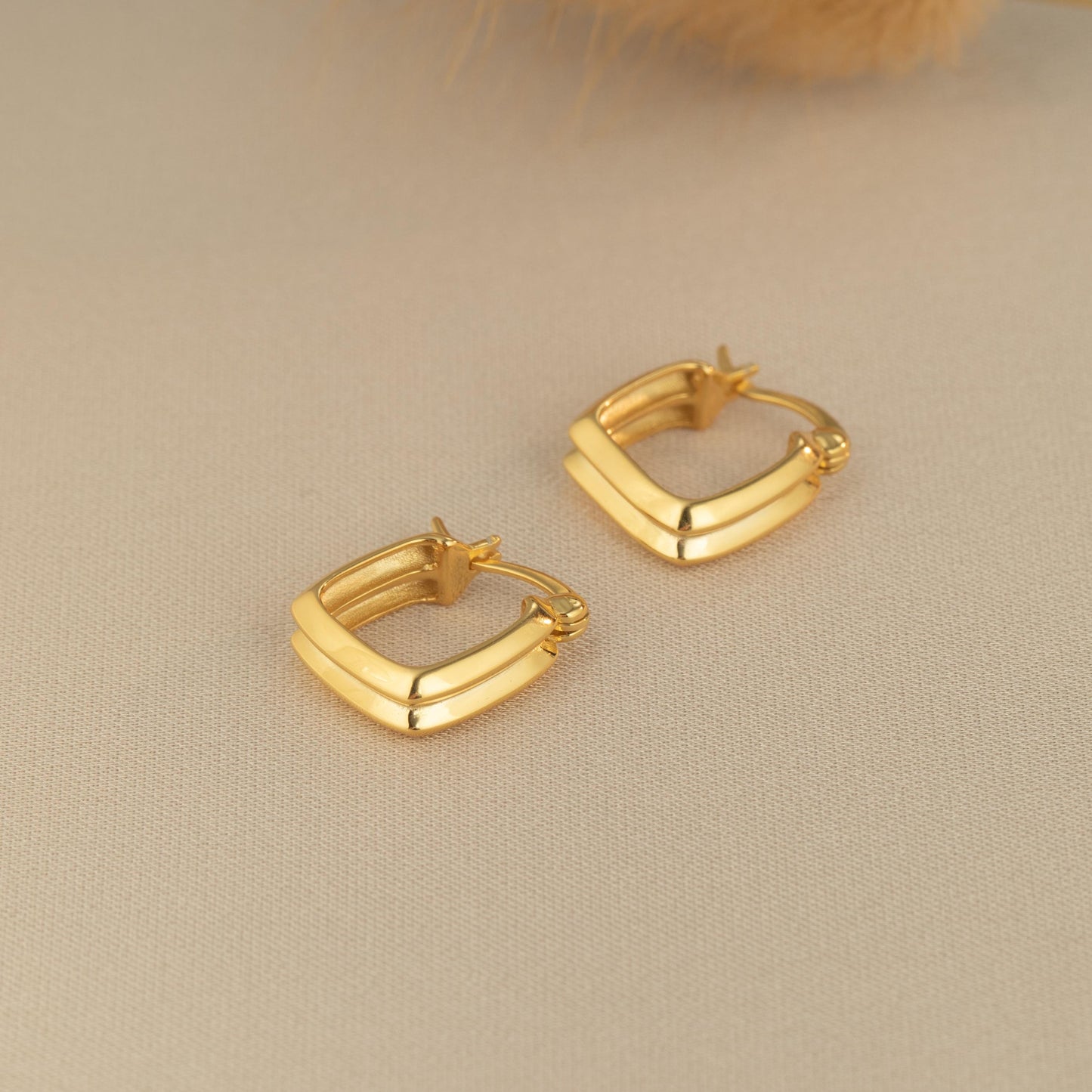 a pair of gold earrings sitting on top of a table