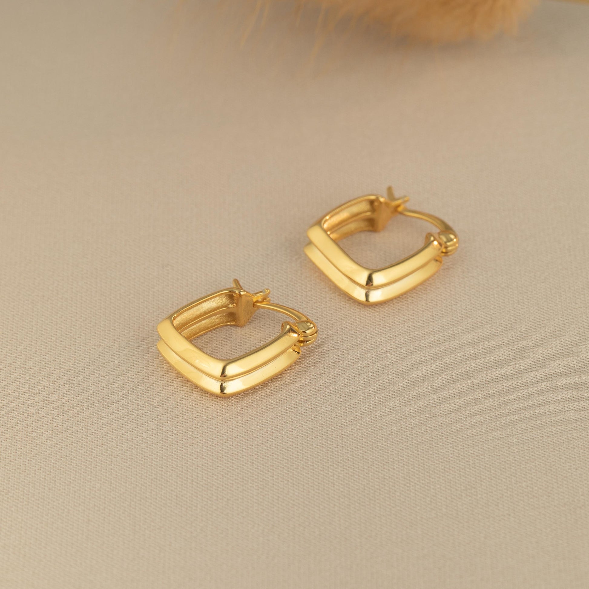 a pair of gold earrings sitting on top of a table