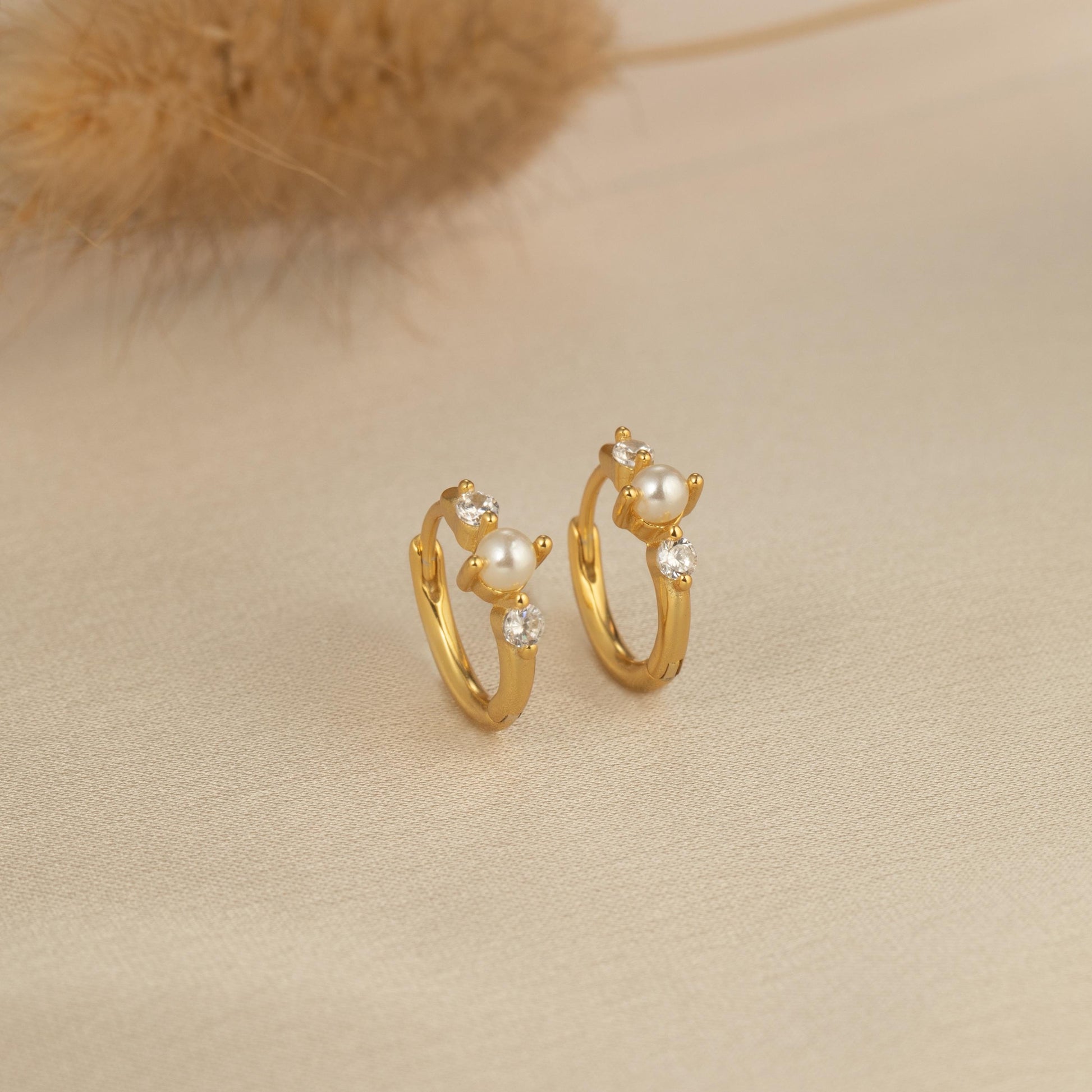 a pair of gold hoop earrings with pearls