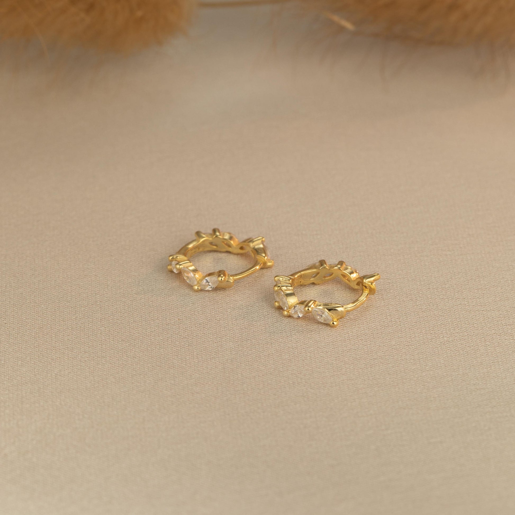a pair of gold earrings sitting on top of a table