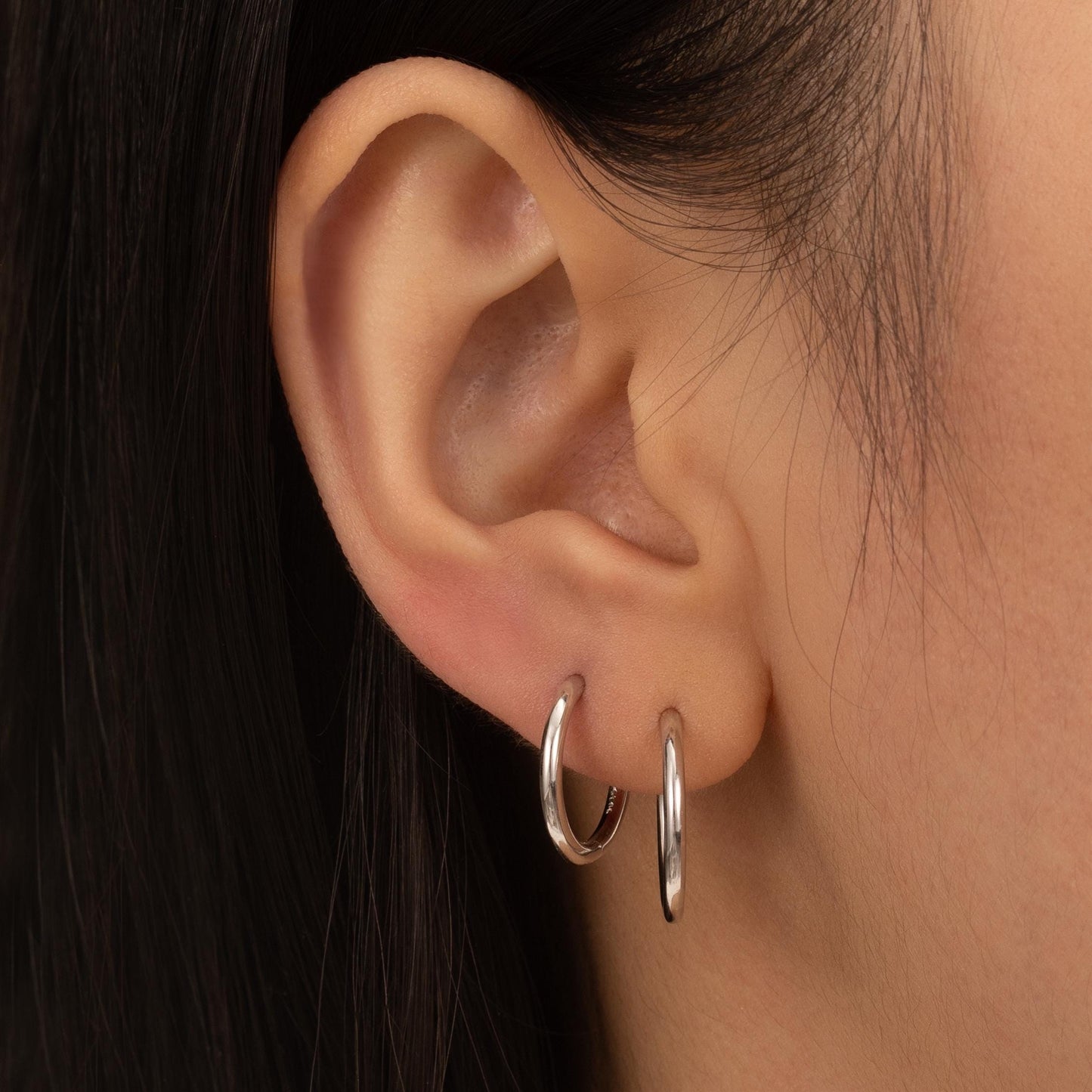 a close up of a person wearing a pair of hoop earrings