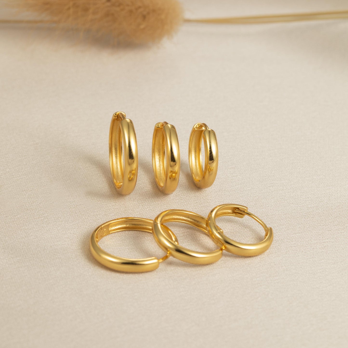 three pairs of gold rings on a white surface