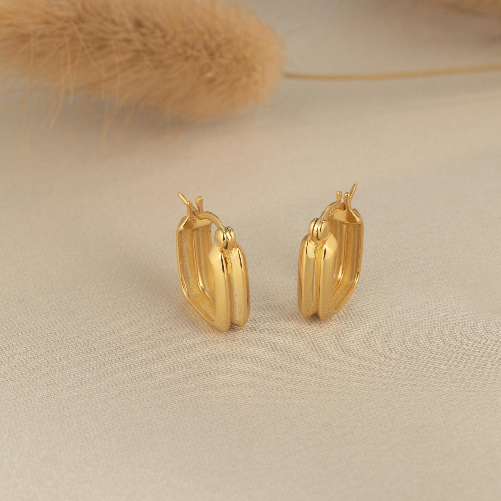 a pair of gold earrings sitting on top of a table