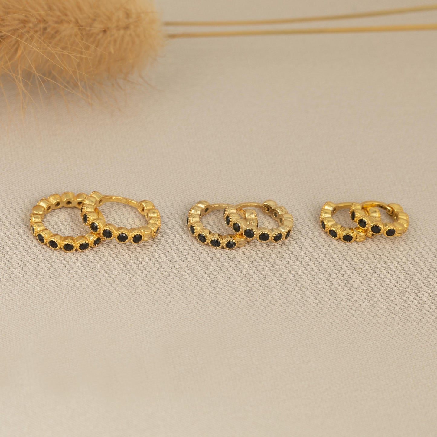three pairs of gold earrings sitting on a table