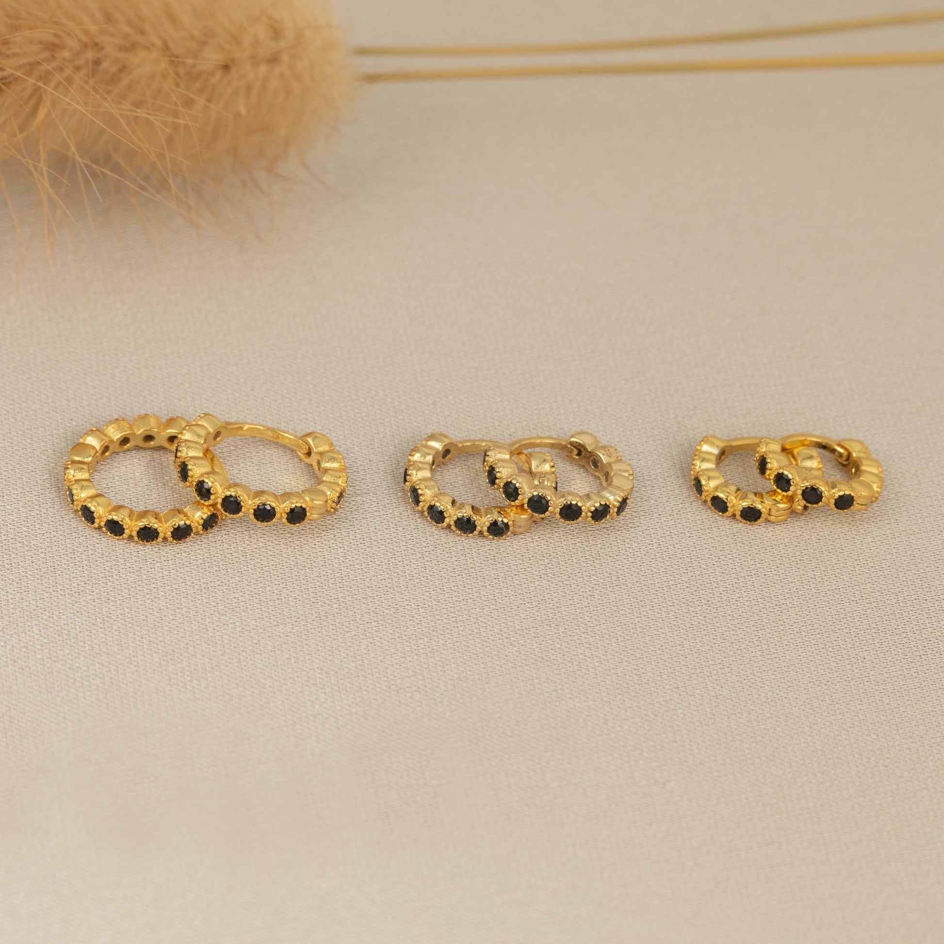 three pairs of gold earrings sitting on a table