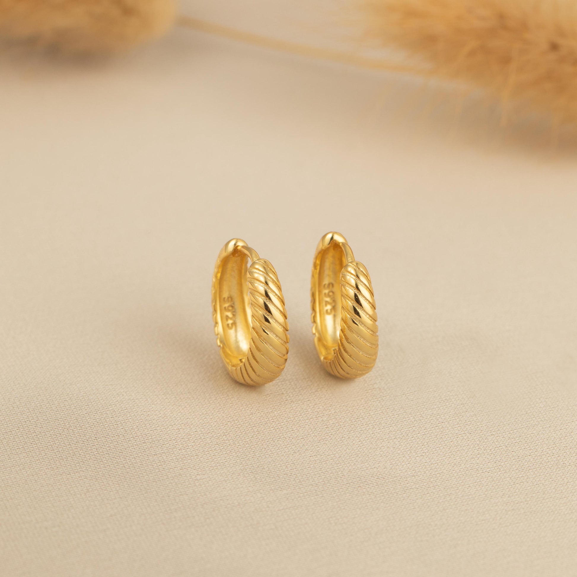 a pair of gold earrings sitting on top of a table