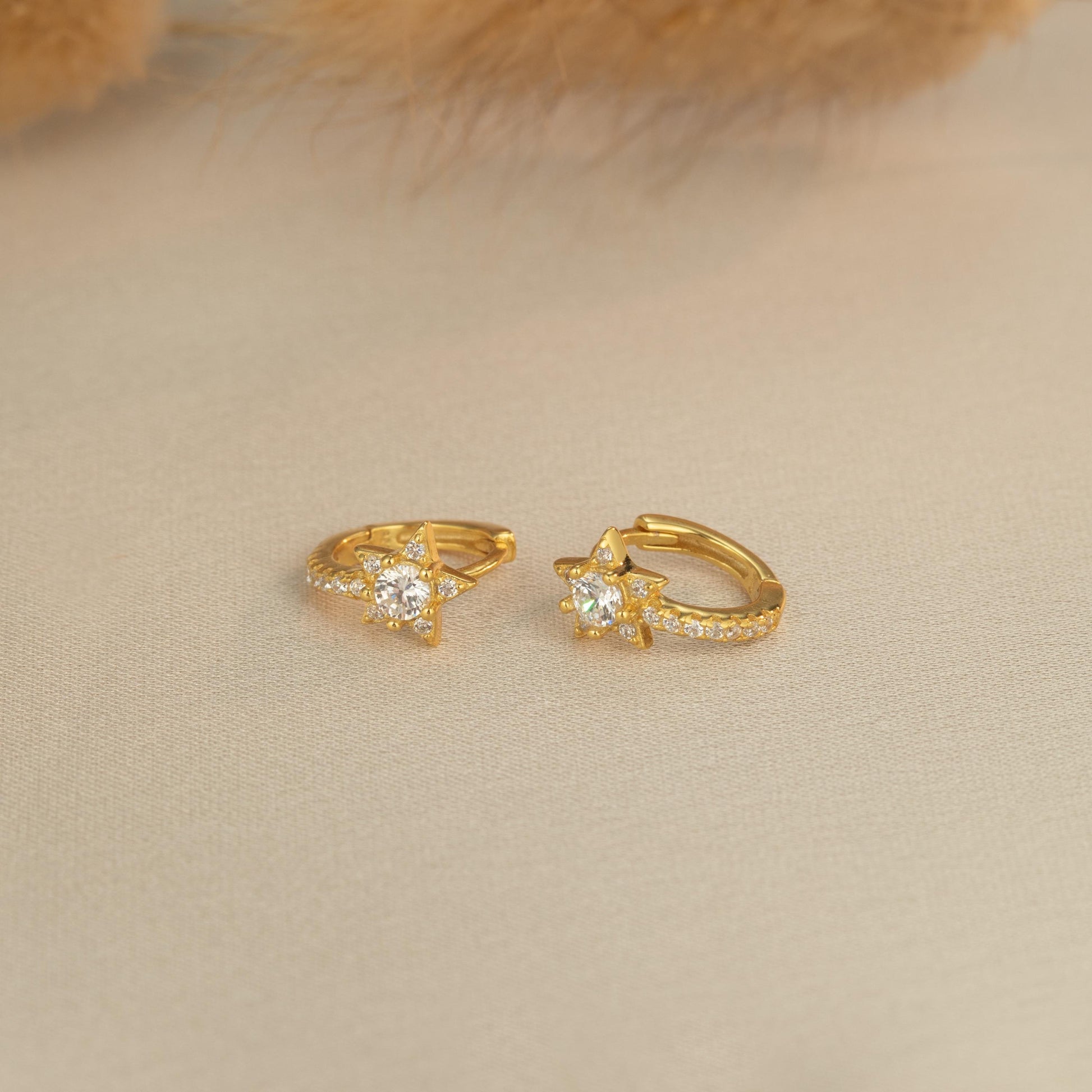 a pair of gold earrings sitting on top of a table