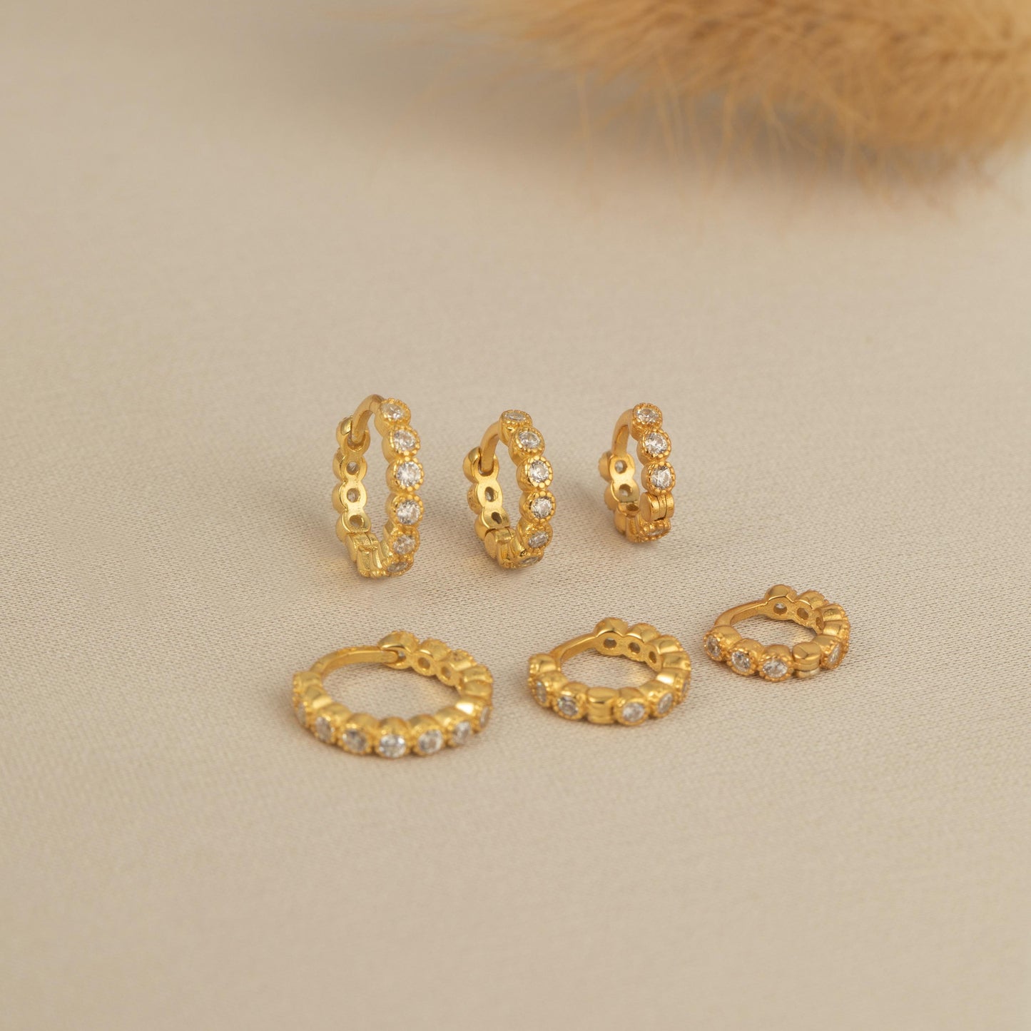 a set of five gold - plated earrings and a feather