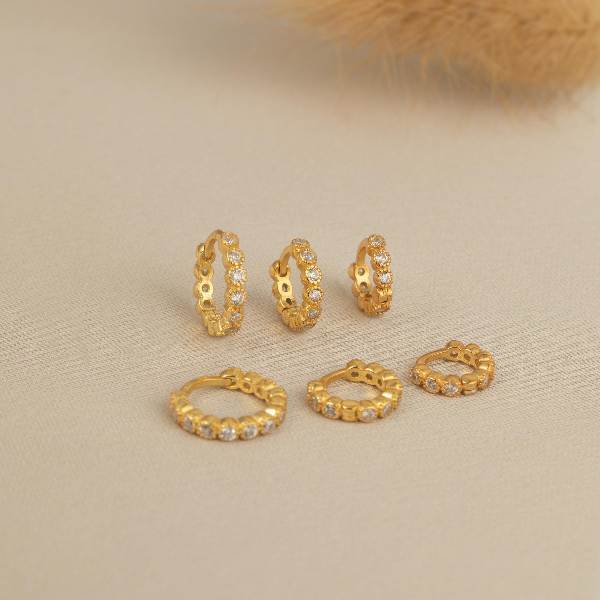 a set of five gold - plated earrings and a feather