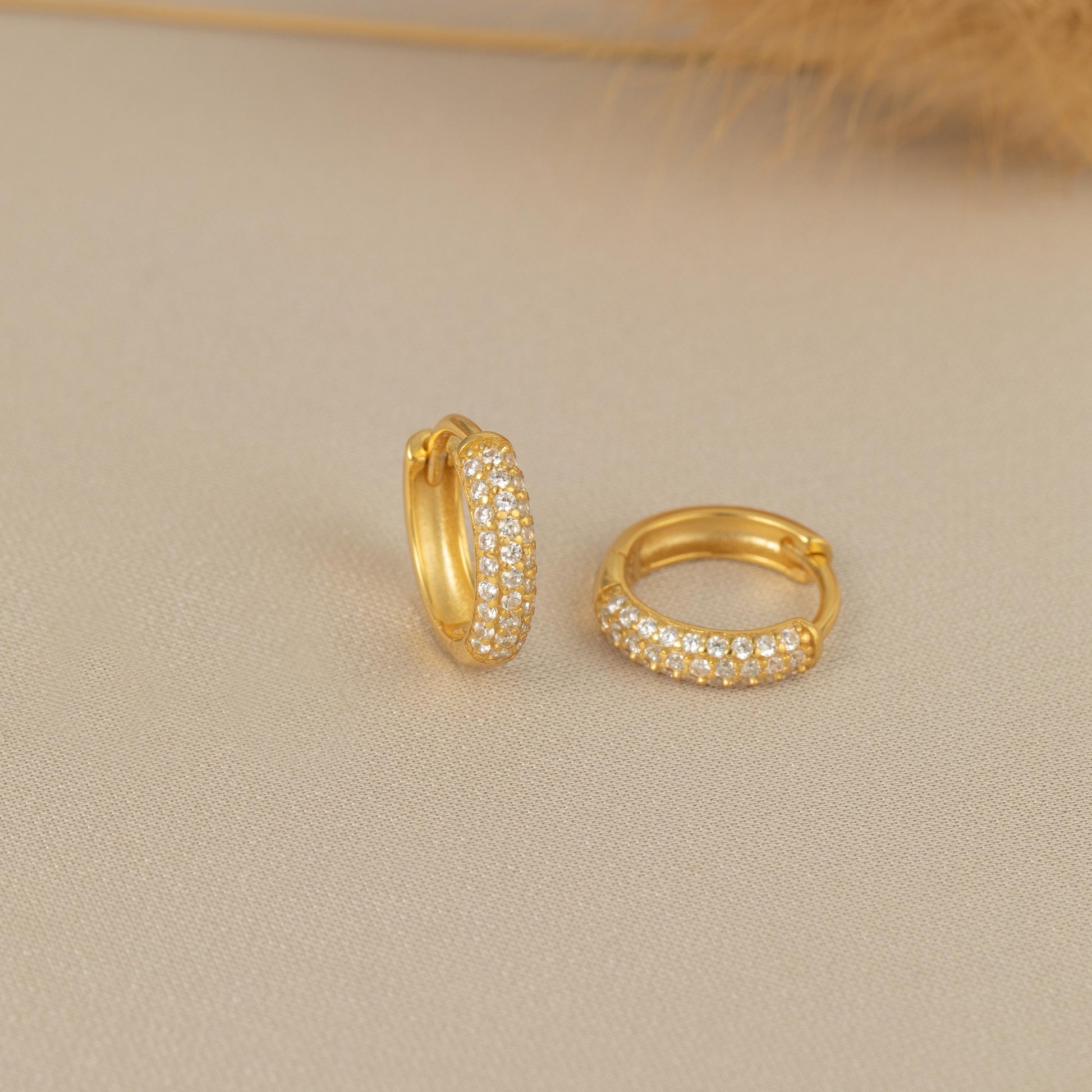 a pair of gold hoop earrings on a white surface